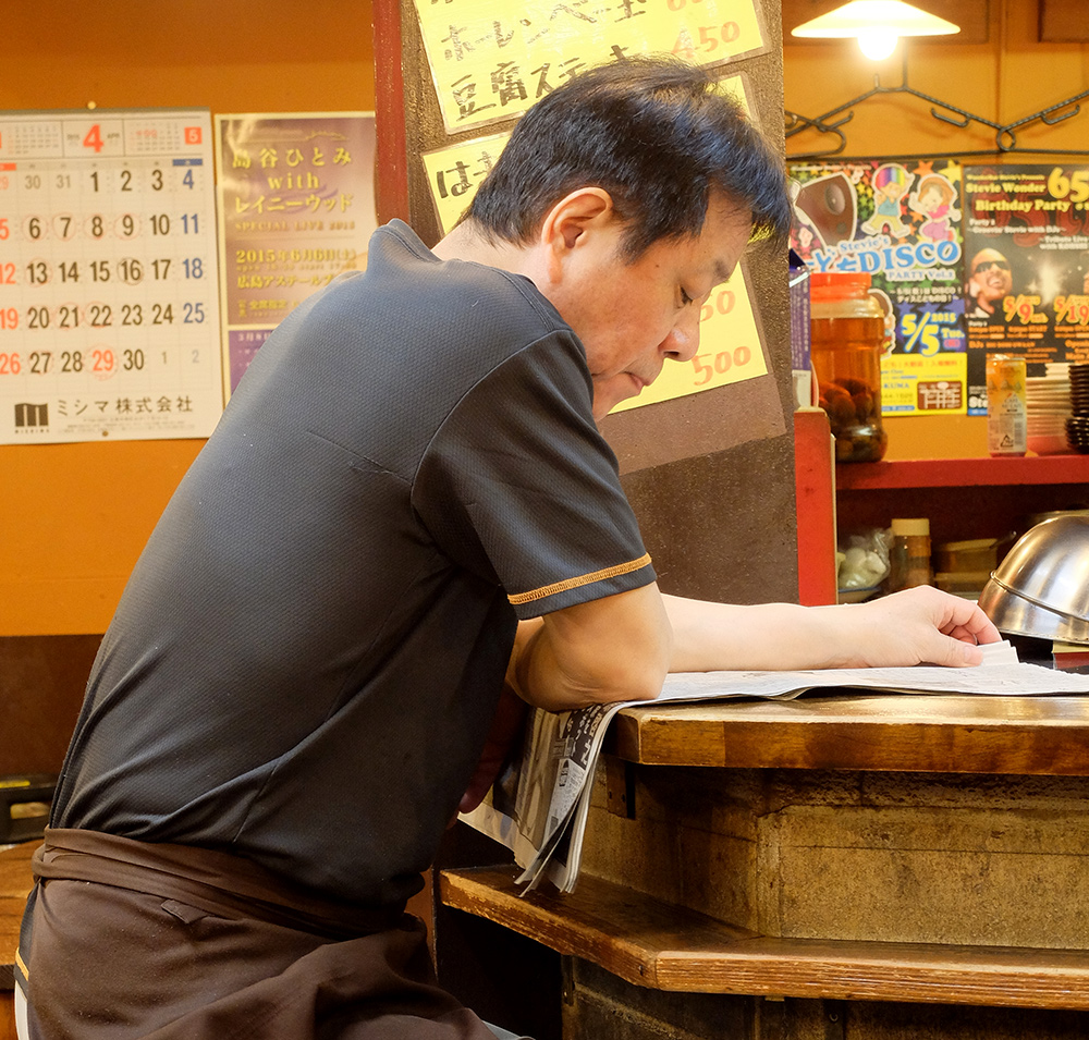 Propriétaire de yatai lisant son journal à Ganko Yatai