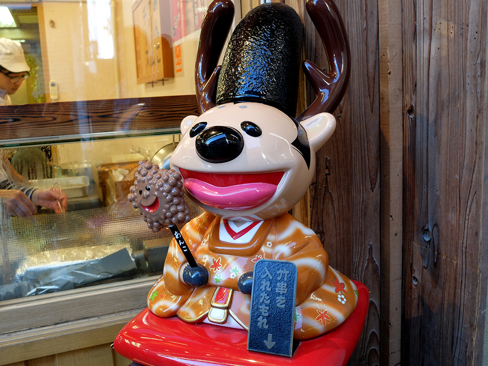 Figurine de biche-prêtre shinto avec un age-momiji-manju (pâtisserie en forme de feuille d'érable frite)